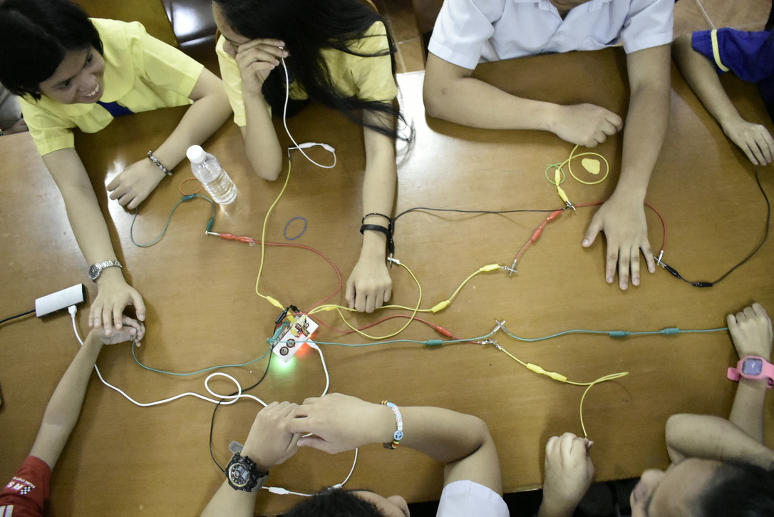 Students touching a conductive board connected with jumper wires